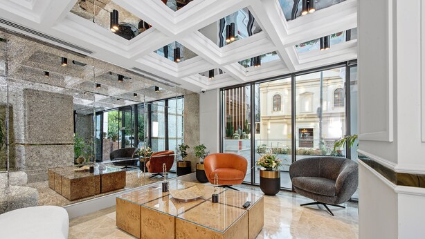 A modern lobby with a glass coffee table, seating area, and large windows offering views of the city. - IBOS HOTELS IZMIR (Izmir)
