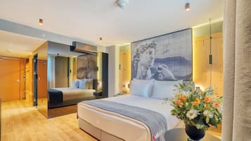 A modern hotel room with a large bed, a mirror, a wall-mounted artwork, and a vase of flowers.