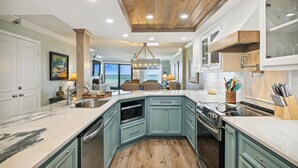 A spacious kitchen with teal cabinetry, a large island, and a view to the outdoors. - IR 105 Beautiful Gulf Front Remodeled 2 bedroom (Destin)