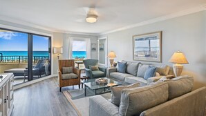 A spacious living room with a view of the ocean, a balcony with outdoor seating, and a large window. - IR 105 Beautiful Gulf Front Remodeled 2 bedroom (Destin)