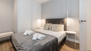 Ein modernes Schlafzimmer mit einem großen Bett, Nachttischen und einem Kleiderschrank.