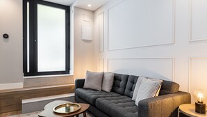 Ein modernes Wohnzimmer mit einem grauen Sofa, einem kleinen runden Tisch mit Tablett und einer Lampe auf einem Beistelltisch.