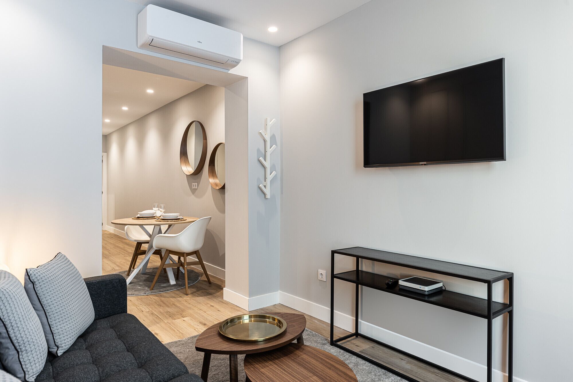 Una sala moderna con sofá, mesa de centro, televisor y comedor con mesa y sillas.
