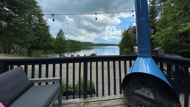 Een terras met een blauwe barbecue, een bank en uitzicht op een meer.