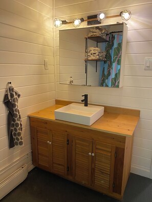 A bathroom with a wooden vanity, a white sink, and a mirror with lights above. - Willow Cabin - North Frontenac Lodge (Ompah)