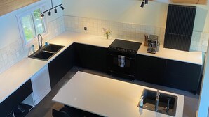 Een moderne keuken met een houten plafond, een centraal eiland met zitplaatsen, een ingebouwde oven en een plafondventilator.