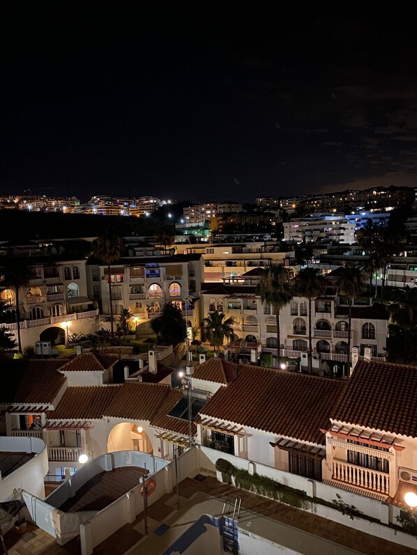 A nighttime view of a coastal town with buildings featuring red-tiled roofs and white walls.
