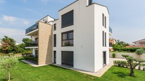 Un moderno edificio residencial de dos pisos con techo plano, ventanas amplias y fachada de piedra.