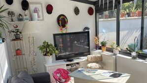 A modern living room with a grey sofa, a coffee table, a TV, and various decorative items including plants and wall art.