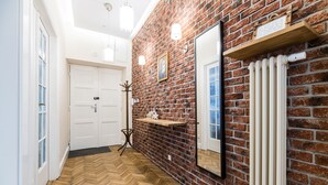 A hallway with a herringbone wooden floor, a brick wall, a white door, and a radiator. - Native Apartments Batorego 7 (Kraków)