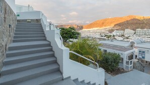 A staircase leading to a rooftop with a view of a cityscape and mountains. - 2BR Private Terrace House-Solarium & Pool (Mogán)