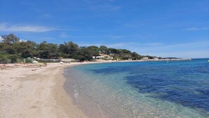 Una playa con aguas cristalinas y poco profundas, orilla de arena y edificios a lo largo de la costa.