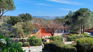 Zona residencial con casas, abundante vegetación y una vista despejada del mar al fondo.
