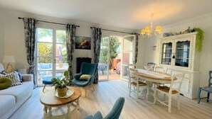 Un salón amplio con un sofá, una mesa de comedor con sillas, un sillón azul y una chimenea.