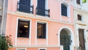 Un edificio de varios pisos con fachada rosa, ventanas grandes y una entrada central con arco.