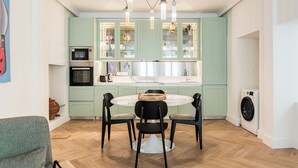 Una cocina moderna con comedor, que incluye una mesa redonda con sillas, horno empotrado y lavadora.