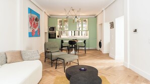 Una sala de estar moderna con un sofá, sillas, una mesa de centro y un comedor con una mesa y sillas.