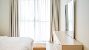 A bedroom with a bed, a dresser, and a large mirror. - Yogi - Elegant Apartment With Balcony Amidst Vibrant Area (Dubai)