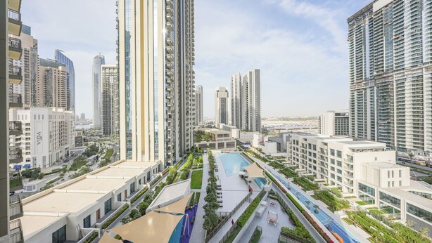 A high-rise residential building complex with multiple apartment buildings, a central courtyard with a swimming pool, and a well-maintained green space. - Yogi - Elegant Apartment With Balcony Amidst Vibrant Area (Dubai)