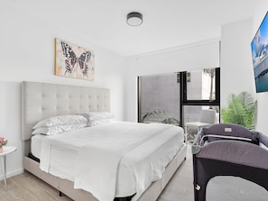 A modern bedroom with a large bed, a wall-mounted TV, and a window with a view of the outdoors. - X Lounge III-Modern Corner Residence (Miami)