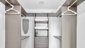 A modern closet with a built-in ironing station, a hanging garment rack, and a patterned ironing board.