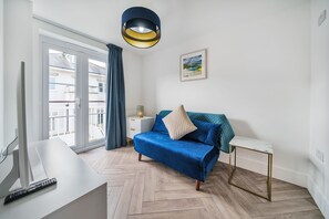 A modern living room with a sofa, a side table, a lamp, and a painting on the wall.