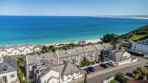 Un quartier résidentiel situé sur la côte, avec des maisons, une plage et une vue dégagée sur la mer.