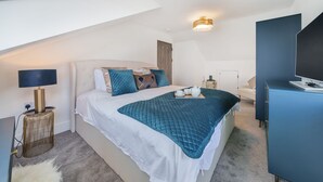 Un dormitorio moderno con cama, mesita de noche, lámpara y escritorio con ordenador.