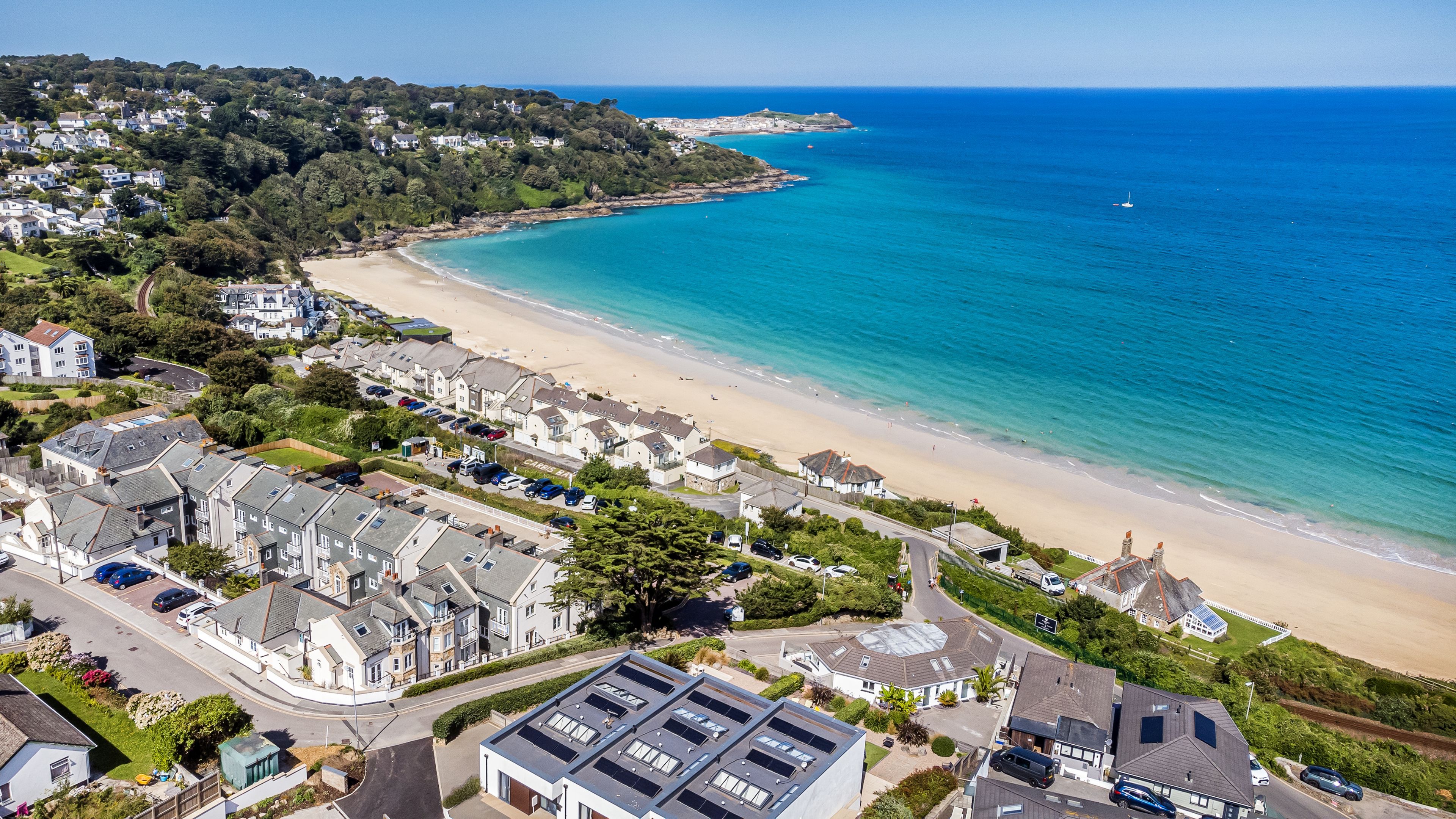 A coastal residential area with houses, a beach, and a clear view of the sea.