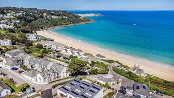 A coastal residential area with houses, a beach, and a clear view of the sea.