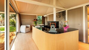 A modern reception area with a wooden reception desk, a black countertop, and a large window offering a view of the outdoors.