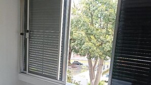 Ein Zimmer mit großem Fenster, weißen Wänden und Holzboden.