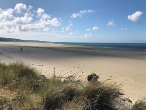 A beach with sand and sparse vegetation in the foreground. - Maison Urville-nacqueville a 50m de la Plage (La Hague)