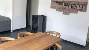 A modern dining area with a wooden table and chairs, a black pendant light, and a wall with a series of landscape photographs.