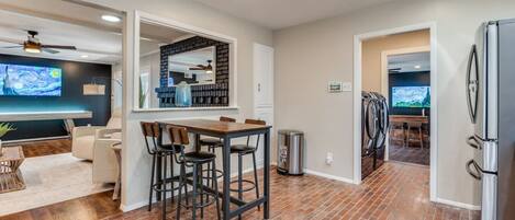 A modern kitchen with a brick floor, a dining area with bar stools, and a large mirror above the counter.
