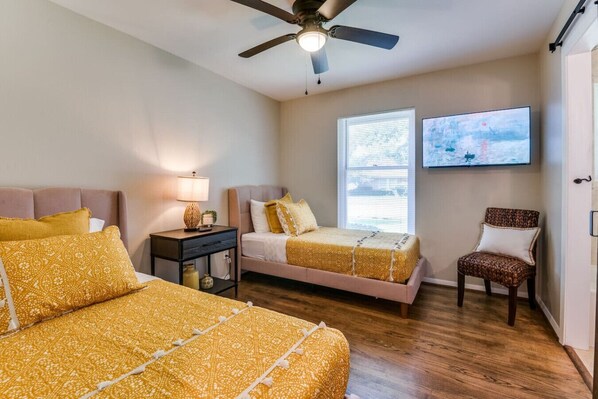 A bedroom with two beds, a chair, a TV, and a ceiling fan. - Heated Pool, Shuffleboard, Putting Green, GM RM! (Dallas)