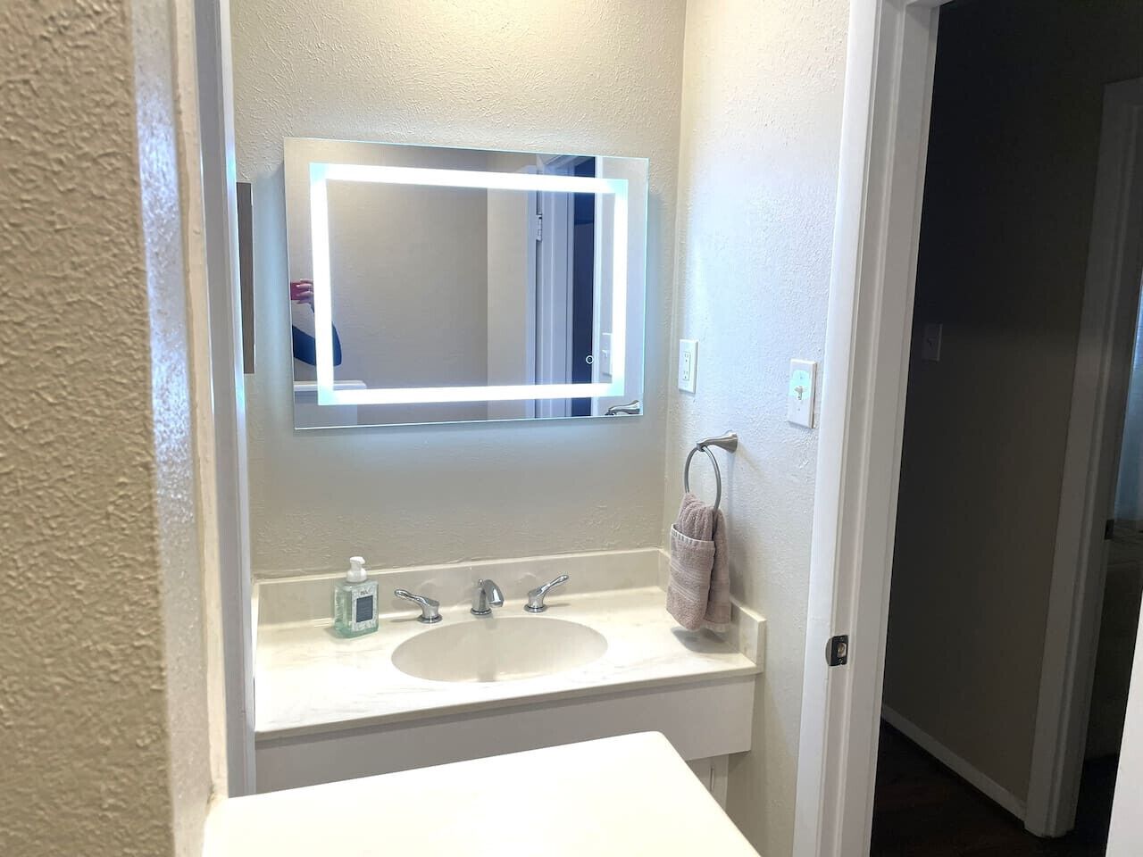 A bathroom with a white sink, a mirror, and a towel rack.