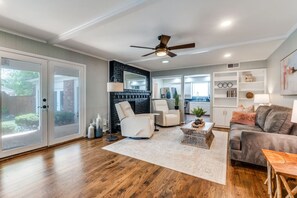 A spacious living room with a large sliding glass door, a ceiling fan, a white sofa, a grey sofa, and a wooden coffee table. - Heated Pool, Shuffleboard, Putting Green, GM RM! (Dallas)