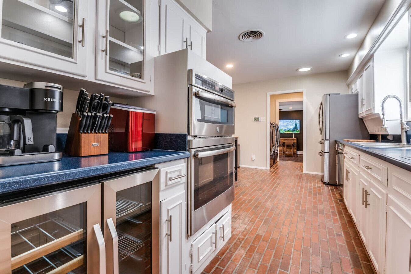 A modern kitchen with stainless steel appliances, white cabinetry, and a blue countertop.