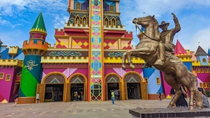 A colorful castle-like building with a central tower and a statue of a man on a horse. - Pousada Ametista (Penha)