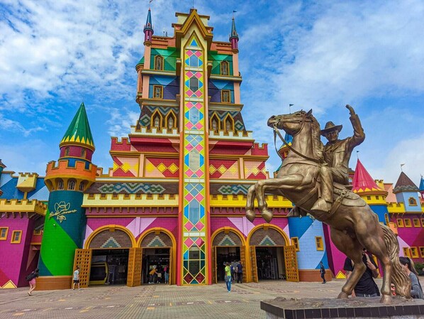 Un colorido edificio que recuerda a un castillo, con una torre central y una estatua de un hombre a caballo.