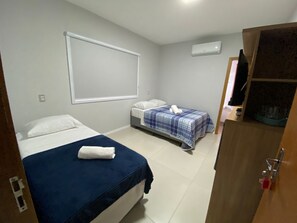 Un dormitorio con dos camas, una ventana y un equipo de aire acondicionado.