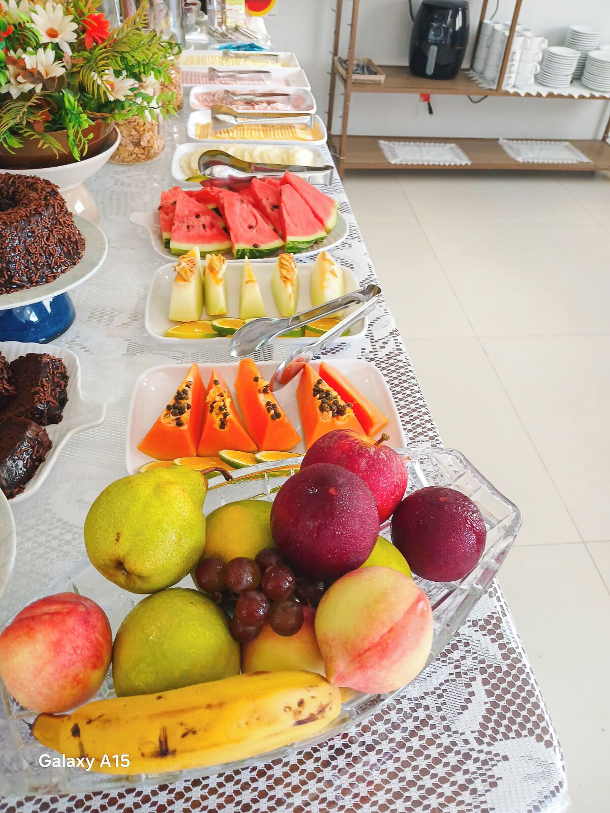 A buffet table with various food items including fruits, desserts, and beverages.