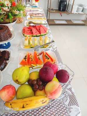 A buffet table with various food items including fruits, desserts, and beverages. - Pousada Ametista (Penha)