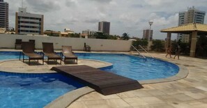A rooftop swimming pool with lounge chairs and a wooden deck. - 1101 Ap Vista mar atrás da passarela (Aracaju)