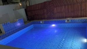 A swimming pool with a blue mosaic tile design, surrounded by a wooden wall with a herringbone pattern. - A Haven of Comfort in Labone, with easy access to essentials amenities (Accra)