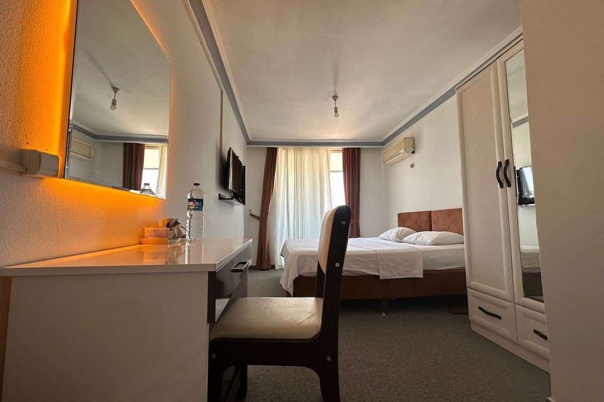 Ein Hotelzimmer mit einem Bett, einem Schreibtisch, einem Sessel, einem Fernseher und einem Kleiderschrank.