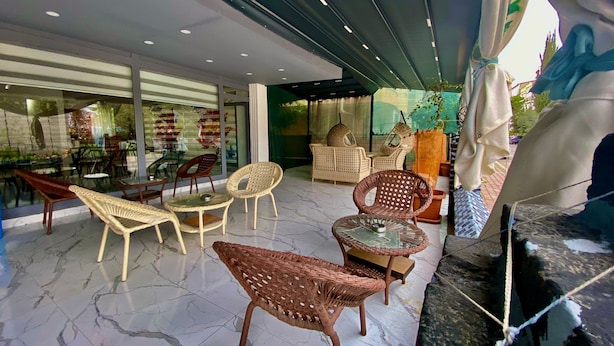 Un espace extérieur moderne, aménagé avec des meubles en osier et une table en verre, entouré d’une terrasse couverte d’où l’on peut admirer la rue.