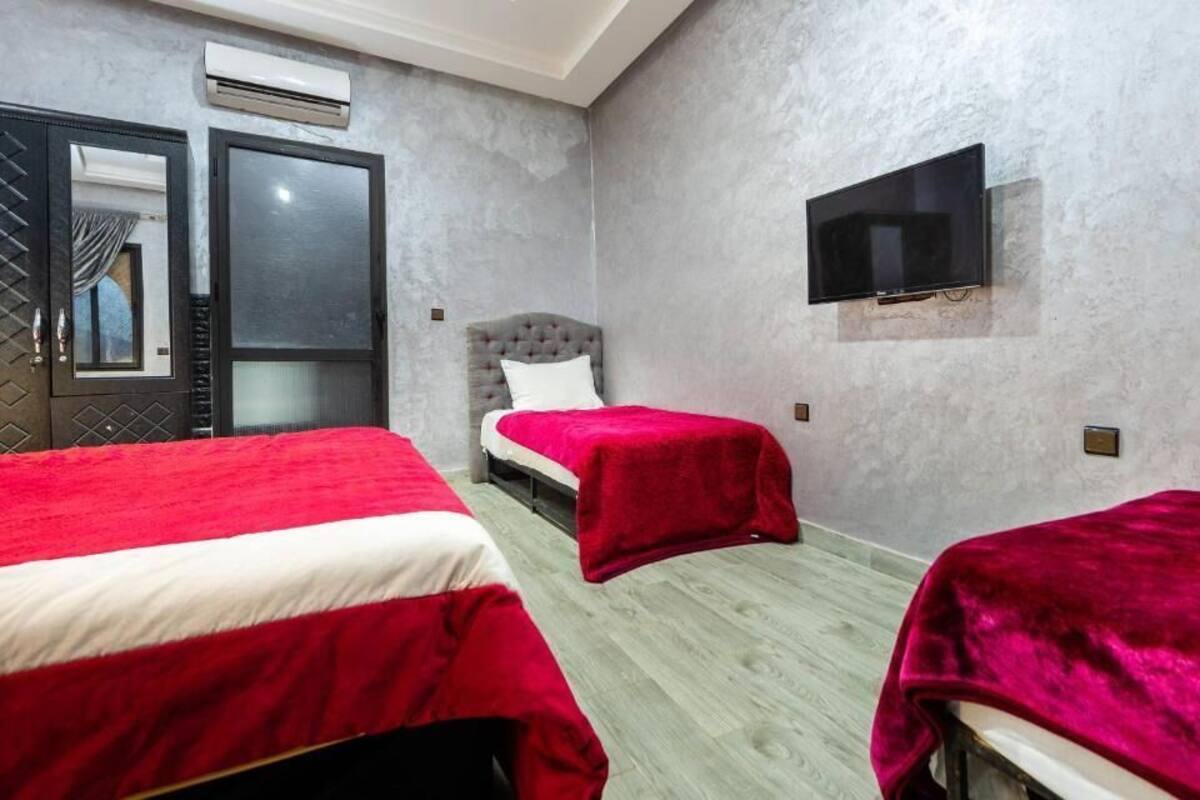 A hotel room with two beds, a television, and an air conditioning unit.