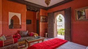 Una habitación con cama, sofá, mesa y puerta que da a un jardín.